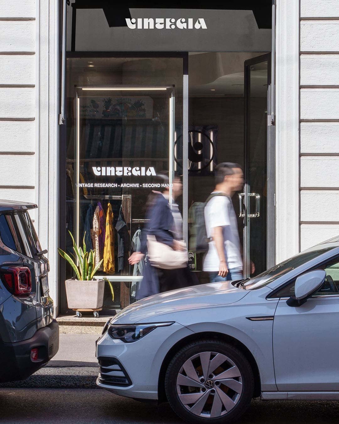 A busy street with cars and a person walking by the exterior of the vintage fashion shop, Vintegia in Milan