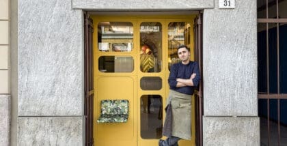 A man outside the yellow door of Coffee Studio 7Gr in Milan
