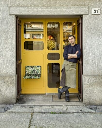 A man outside the yellow door of Coffee Studio 7Gr in Milan