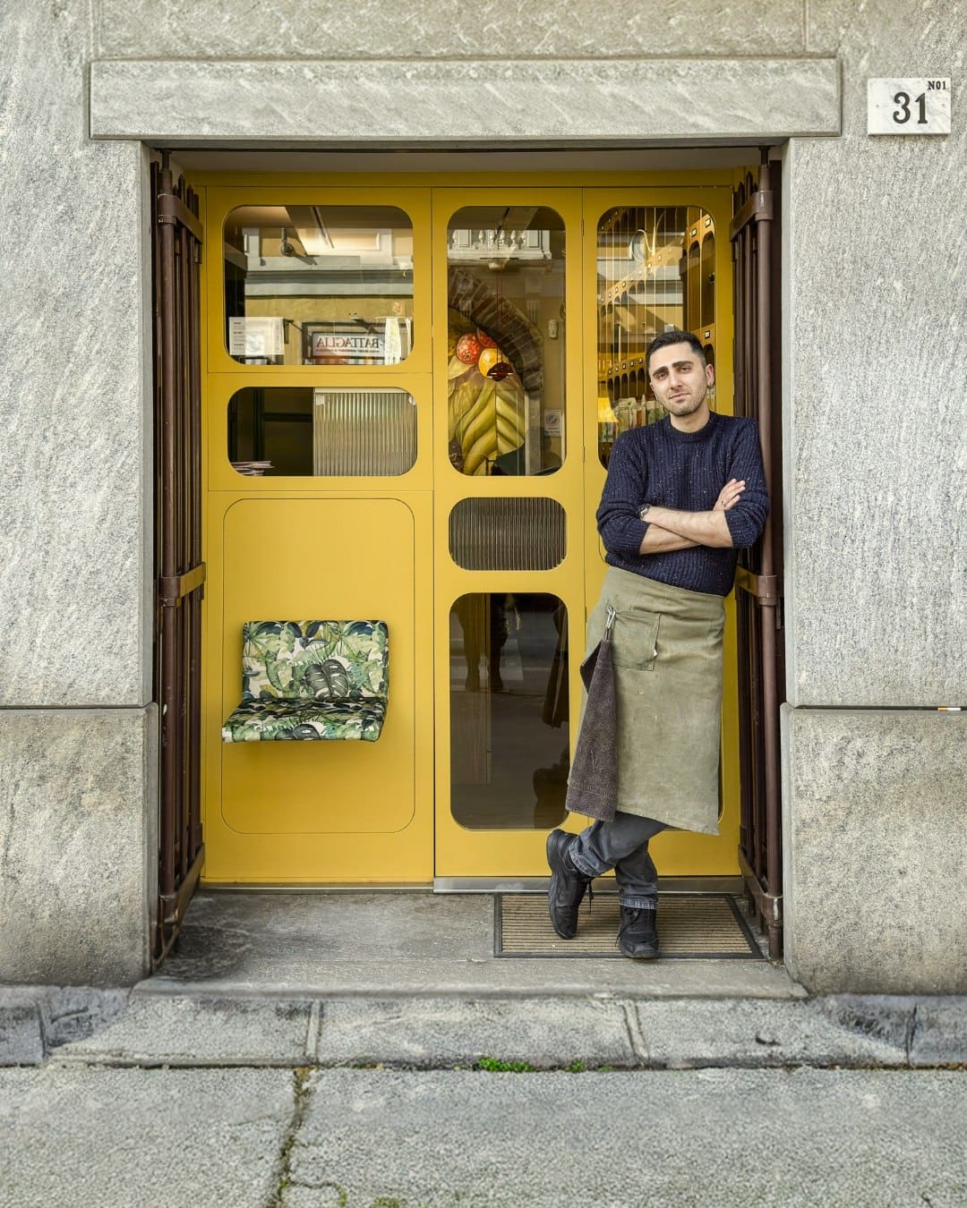 A man outside the yellow door of Coffee Studio 7Gr in Milan
