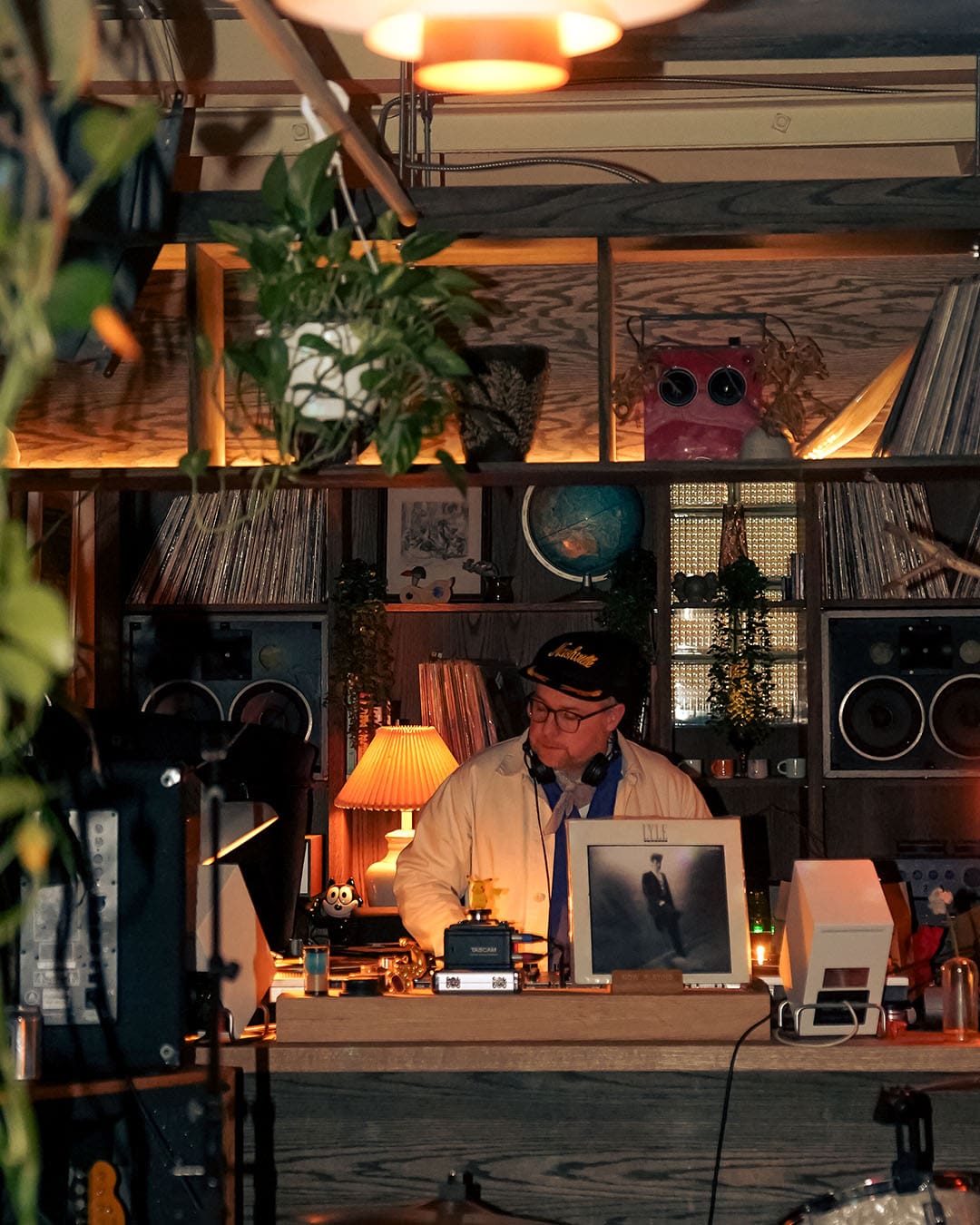 A DJ plays the latest tunes at 915 Dupont surrounded by decks and shelving displaying records and plants