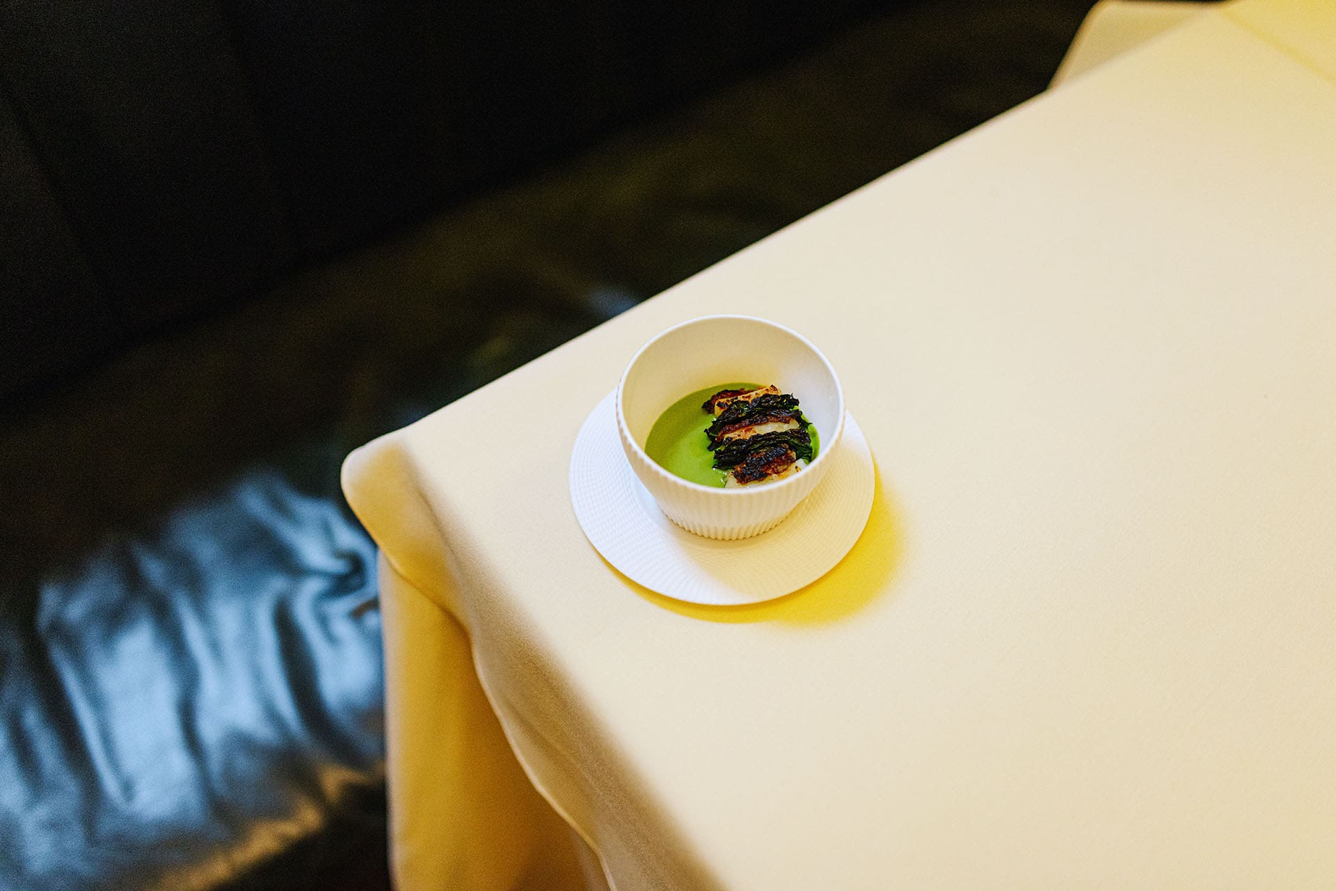 A dish served and photographed compositionally on the edge of table with white table cloth