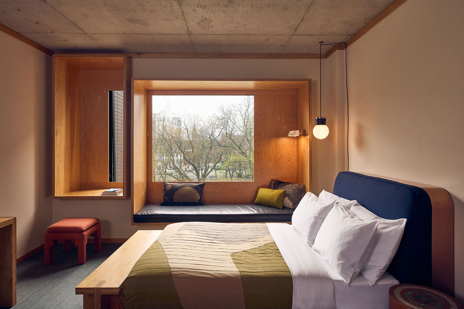 A double bed in a hotel room with a picture window looking out onto a park